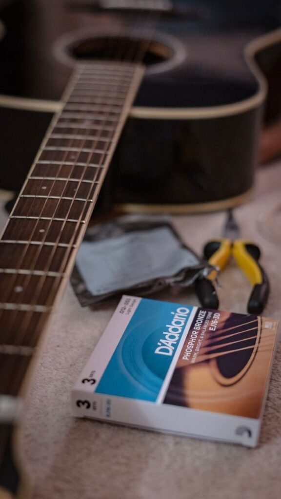 pexels-photo-6024538-6024538 Acoustic guitar close-up with D'Addario strings and guitar tools on a table.
